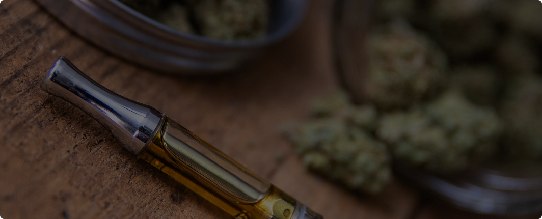 Close-up of a CBD oil dropper and syringe next to ground cannabis material
