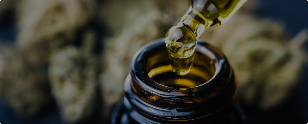 Close-up of CBD oil being dispensed from a dropper into an amber bottle